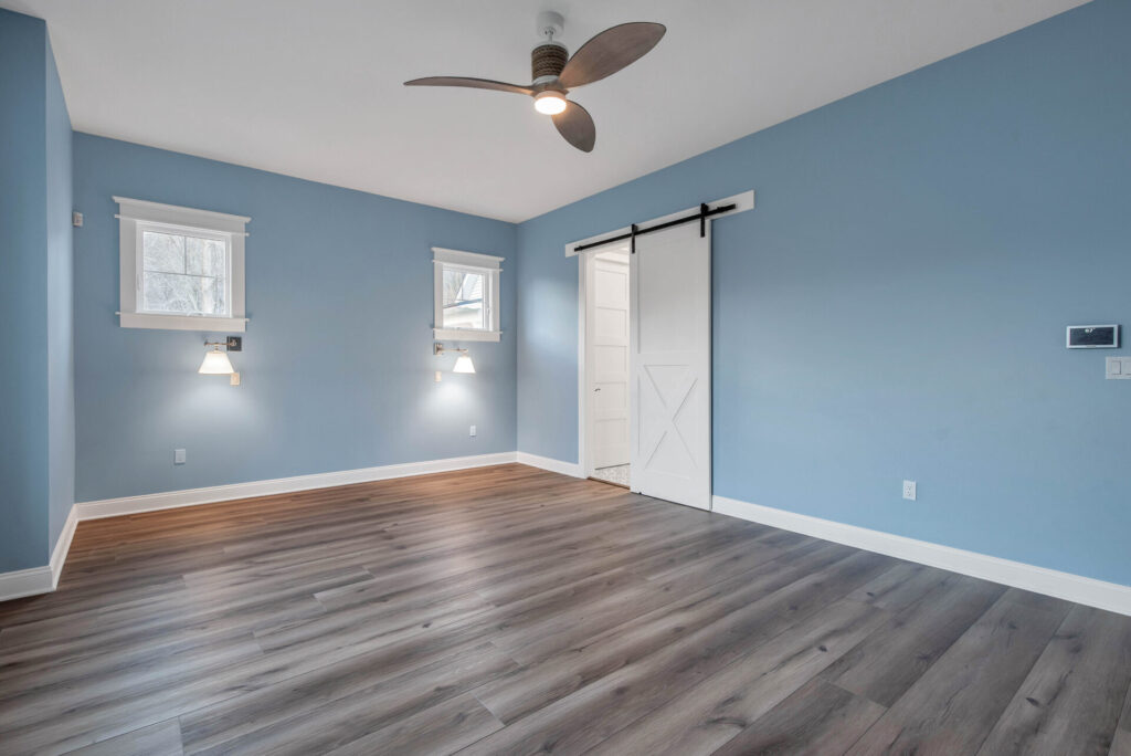 an empty room with blue walls and a ceiling fan