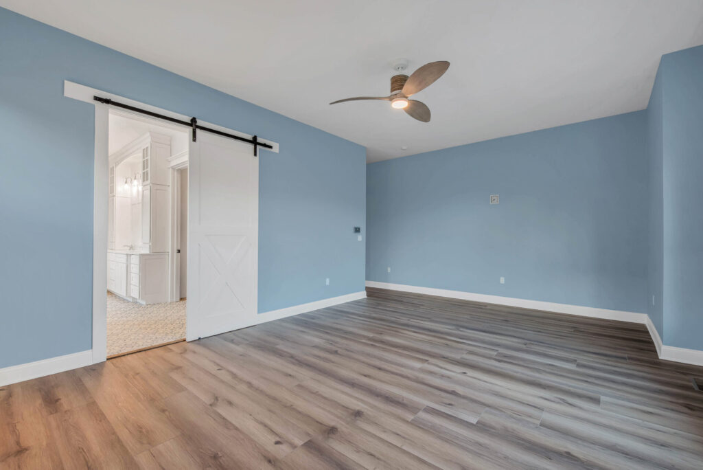 an empty room with blue walls and a ceiling fan