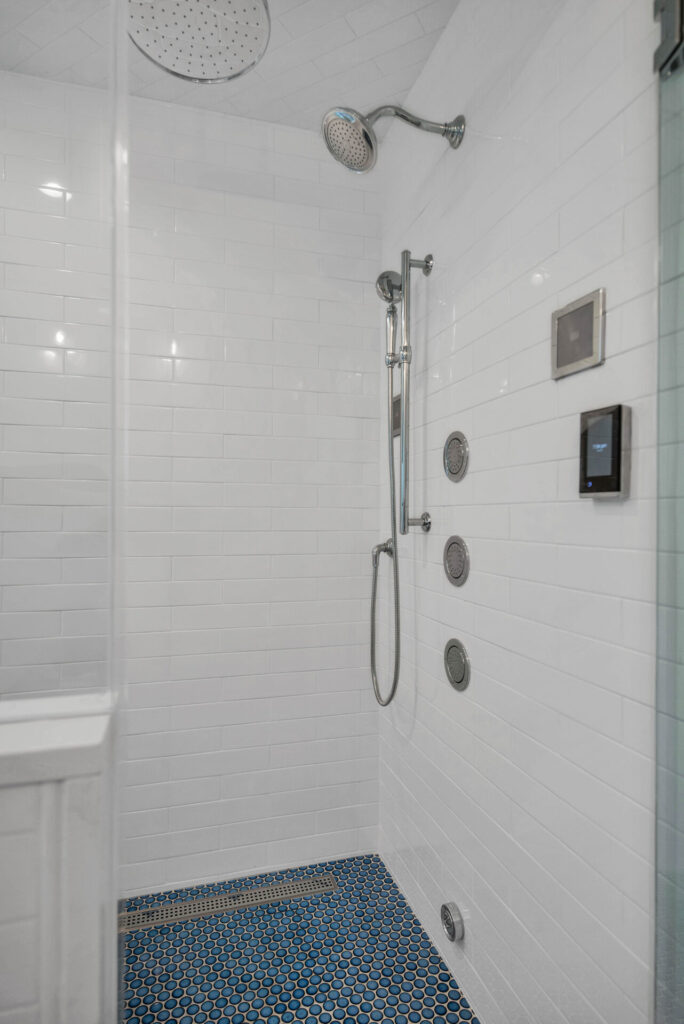 a shower with a blue tile floor and white walls