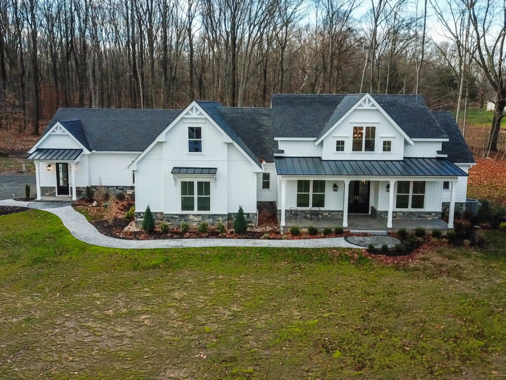 A residential, white farmhouse with front porch remodeled by Fiderio & Sons in Connecticut